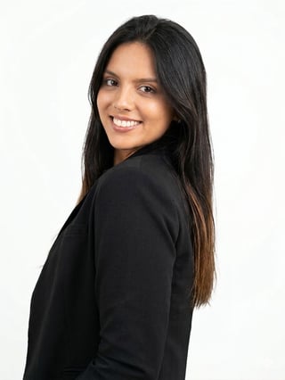 Professional portrait of a smiling woman with long black hair wearing a black blazer, posed over white background